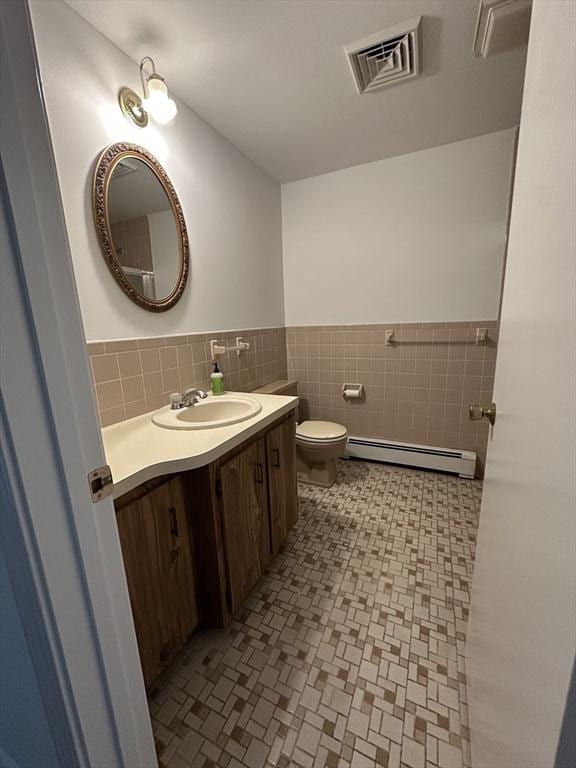 21 Friends Ln, Dennis, MA 02660 - bathroom with a baseboard radiator, vanity, wainscoting, and tile walls