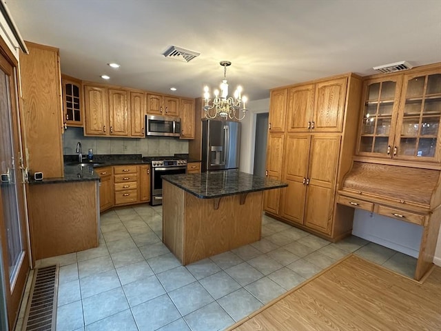 21 Friends Ln, Dennis, MA 02660 - kitchen with appliances with stainless steel finishes, a chandelier, a center island, brown cabinets, and tasteful backsplash