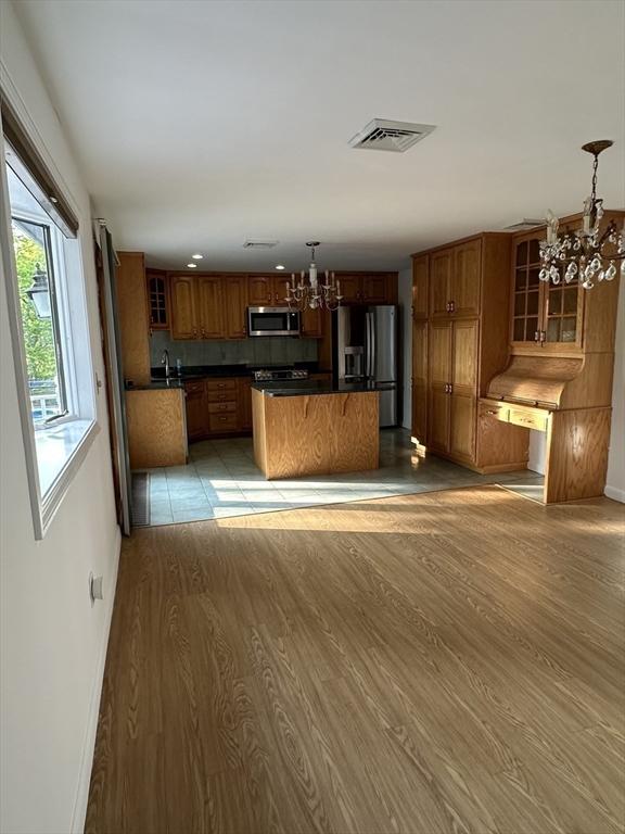 21 Friends Ln, Dennis, MA 02660 - kitchen with stainless steel appliances, a chandelier, dark countertops, light wood finished floors, and brown cabinetry