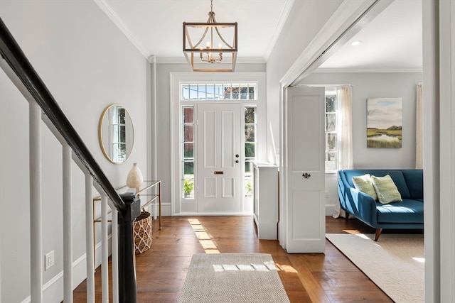 foyer entrance with an inviting chandelier, ornamental molding, and hardwood / wood-style floors