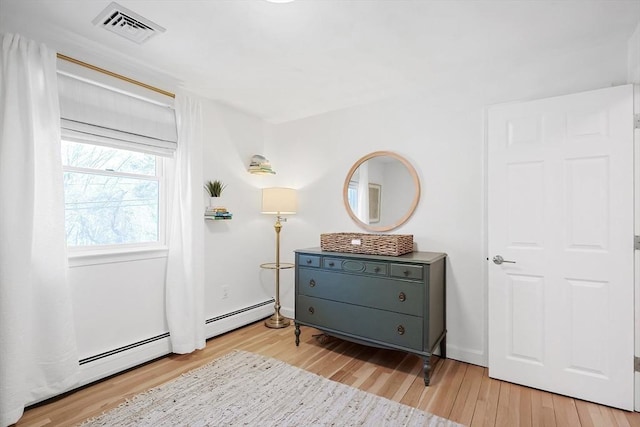 interior space featuring a baseboard radiator, wood finished floors, and visible vents