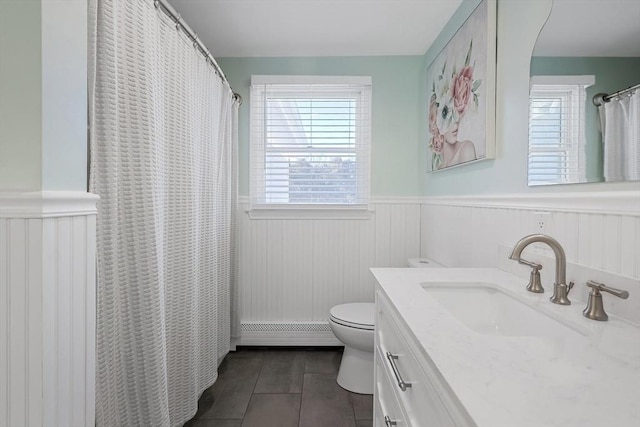 bathroom with toilet, vanity, a baseboard heating unit, and wainscoting