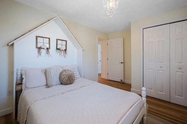 bedroom featuring an inviting chandelier, a closet, baseboards, and wood finished floors