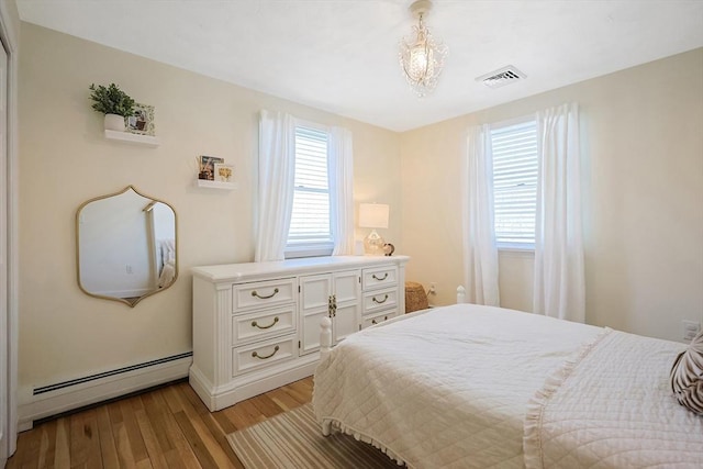 bedroom featuring light wood-style flooring, a baseboard radiator, and visible vents