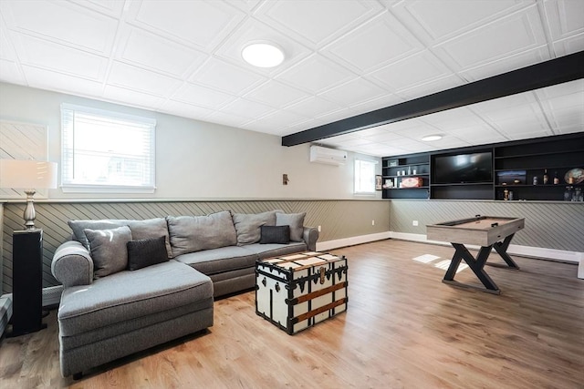 living area with a wainscoted wall, wood walls, a wall mounted AC, and light wood-style floors