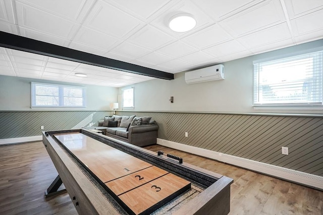 game room featuring a wall unit AC, a wainscoted wall, wood walls, wood finished floors, and baseboards