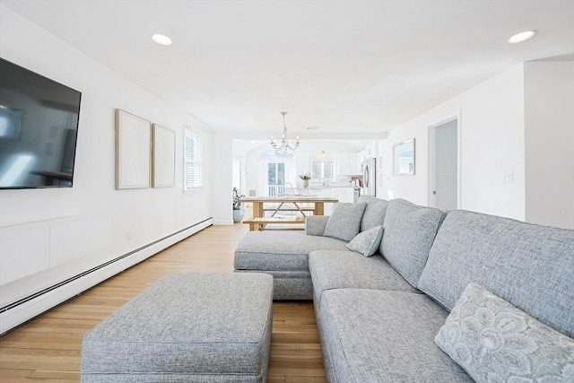 living area with light wood-style floors, a baseboard radiator, a notable chandelier, and recessed lighting