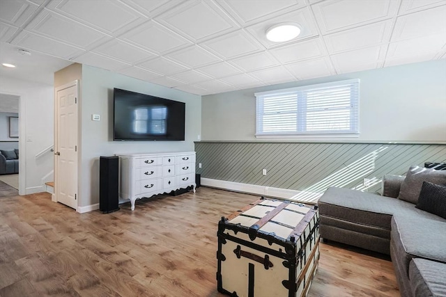 living area with wainscoting, an ornate ceiling, and light wood-style flooring