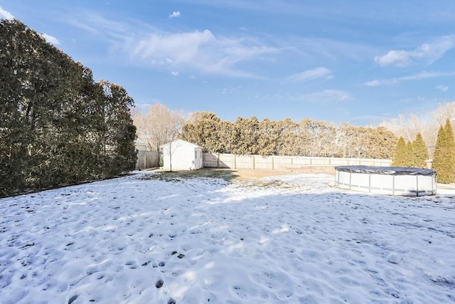 yard layered in snow featuring a fenced backyard and a fenced in pool