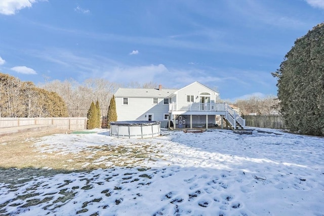 snow covered rear of property featuring stairs, fence, a deck, and a fenced in pool