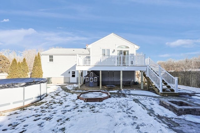 snow covered rear of property with a covered pool, stairs, fence, and a wooden deck