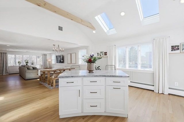 kitchen featuring a wealth of natural light, white cabinets, visible vents, and baseboard heating