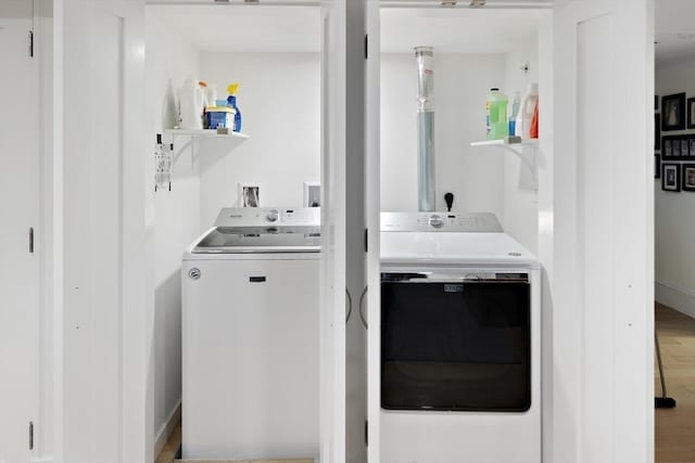 clothes washing area with wood-type flooring and washer and dryer