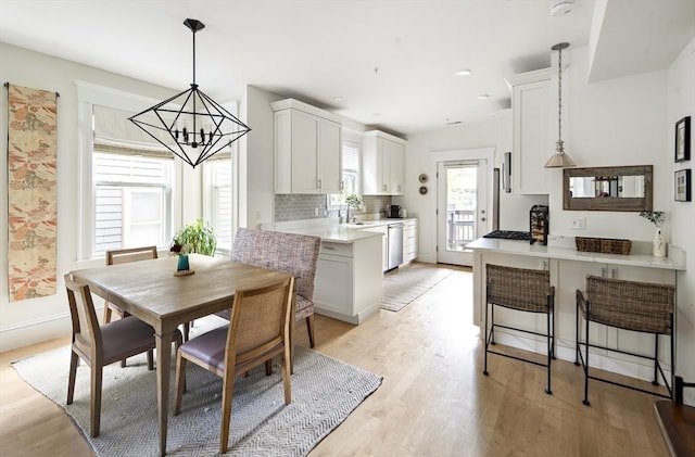 dining room featuring sink, light hardwood / wood-style flooring, and a notable chandelier