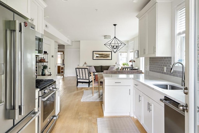 kitchen featuring hanging light fixtures, white cabinetry, appliances with stainless steel finishes, and sink