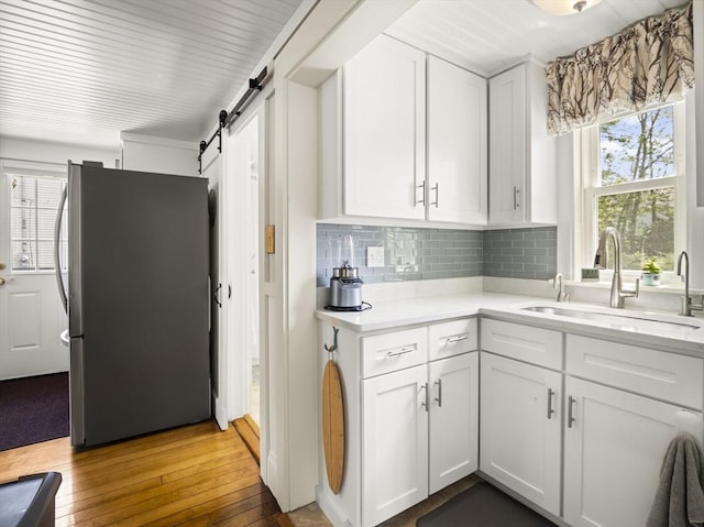 5 Adams St, Littleton, MA 01460 - kitchen with freestanding refrigerator, a barn door, a sink, light countertops, and hardwood / wood-style flooring