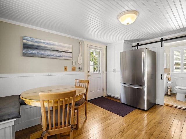 5 Adams St, Littleton, MA 01460 - dining space with a barn door, light wood finished floors, healthy amount of natural light, wainscoting, and wood ceiling