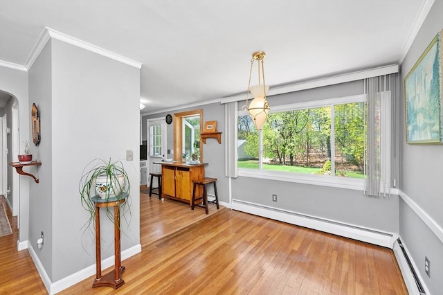 dining space featuring a baseboard heating unit, ornamental molding, hardwood / wood-style flooring, and a baseboard radiator