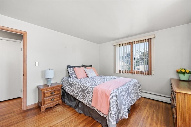 bedroom with wood finished floors and a baseboard radiator