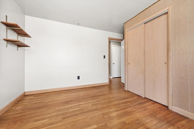 unfurnished bedroom with a closet, light wood-style flooring, and baseboards