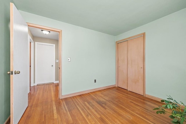 unfurnished bedroom with baseboards, a closet, and hardwood / wood-style floors