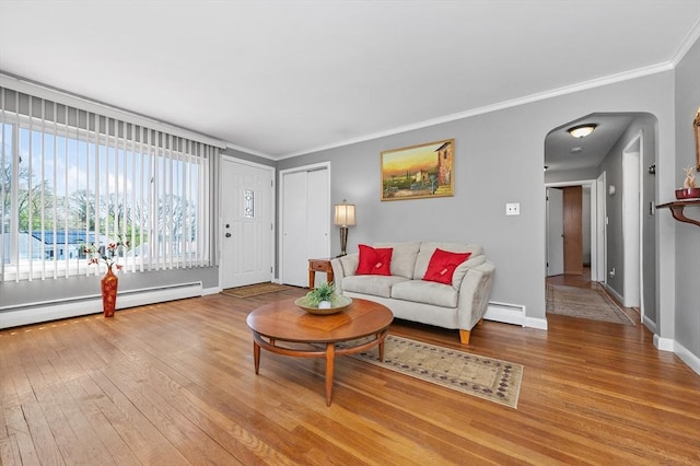 living room featuring arched walkways, hardwood / wood-style flooring, baseboards, a baseboard radiator, and ornamental molding