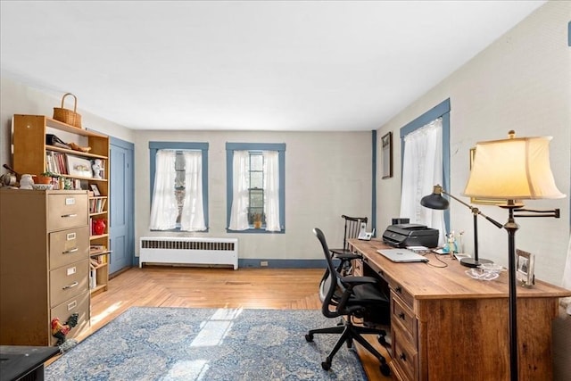 home office featuring parquet flooring, radiator heating unit, and baseboards