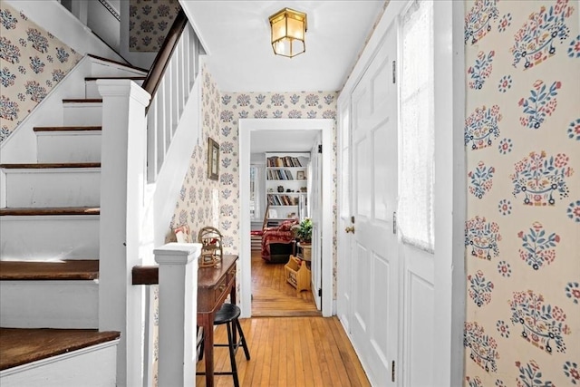 foyer featuring stairs, light wood finished floors, and wallpapered walls