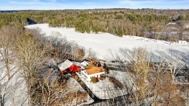 snowy aerial view featuring a wooded view