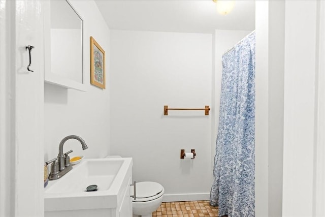 bathroom with toilet, curtained shower, baseboards, and vanity