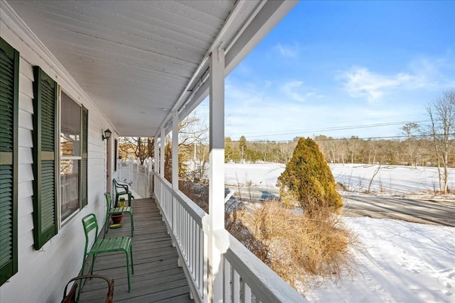 snow covered back of property featuring a porch