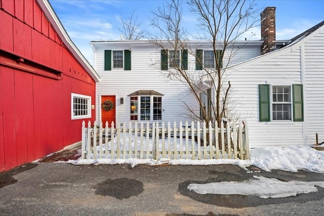 view of front of house with a barn, fence, and an outbuilding