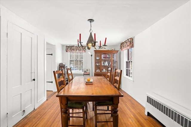 dining space featuring a chandelier, light wood-style floors, and radiator