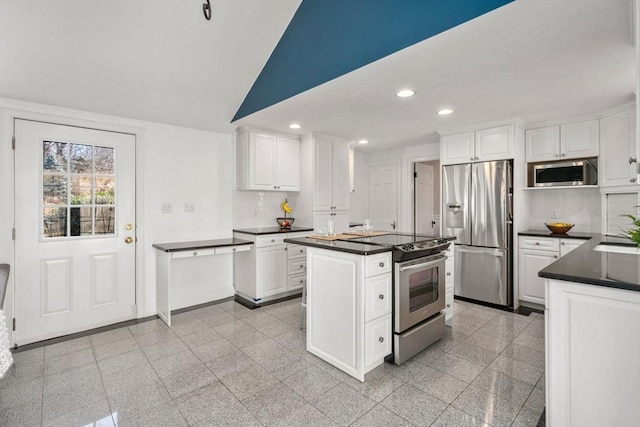 kitchen featuring stainless steel appliances, dark countertops, granite finish floor, and recessed lighting