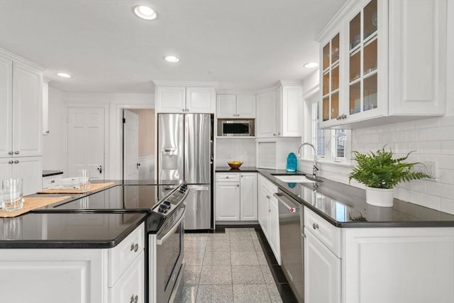 kitchen featuring recessed lighting, dark countertops, granite finish floor, appliances with stainless steel finishes, and a sink