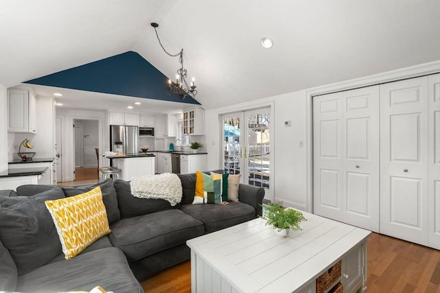 living room with an inviting chandelier, vaulted ceiling, wood finished floors, and recessed lighting