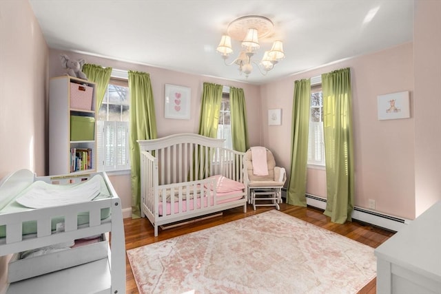 bedroom with a chandelier, a baseboard radiator, and wood finished floors