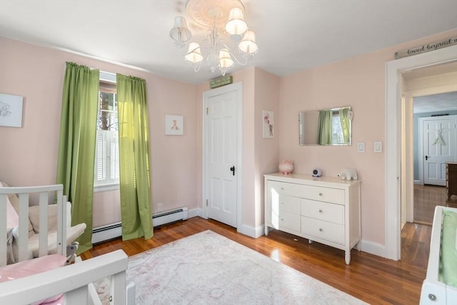 bedroom featuring baseboard heating, baseboards, an inviting chandelier, and wood finished floors