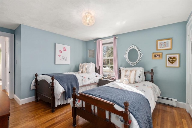 bedroom featuring baseboards, baseboard heating, and wood finished floors