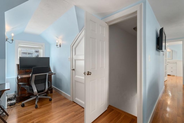 office space with vaulted ceiling, light wood finished floors, and baseboards