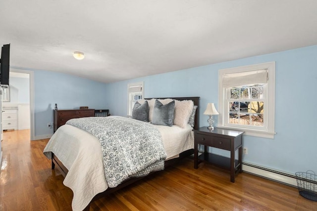 bedroom with baseboards, baseboard heating, and wood finished floors