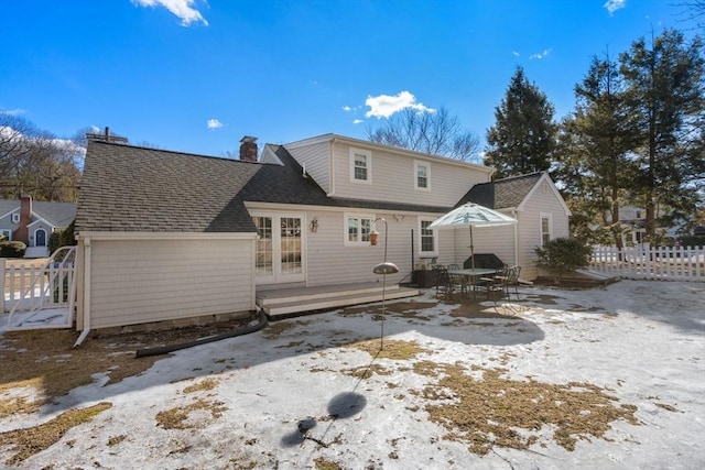 rear view of property with roof with shingles, a chimney, and fence