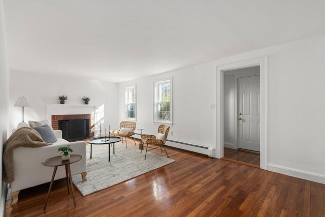 living room featuring a baseboard radiator, a brick fireplace, baseboards, and hardwood / wood-style floors