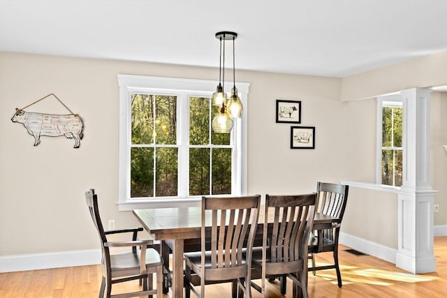 dining room with visible vents, baseboards, light wood-type flooring, and ornate columns