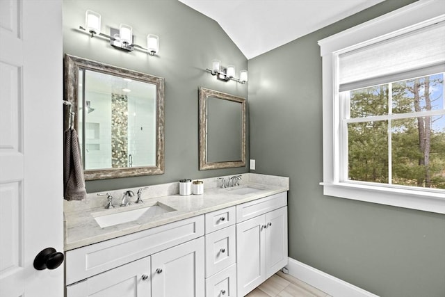 full bath with a sink, baseboards, a shower stall, and vaulted ceiling