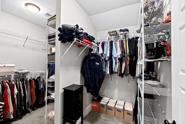 spacious closet featuring lofted ceiling, carpet flooring, and visible vents