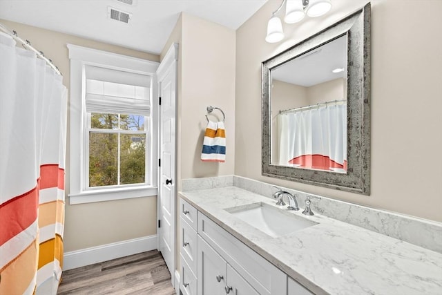 bathroom with visible vents, baseboards, wood finished floors, and vanity