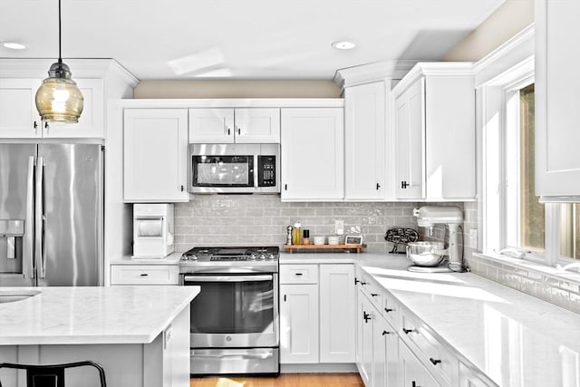 kitchen featuring hanging light fixtures, backsplash, appliances with stainless steel finishes, and white cabinetry