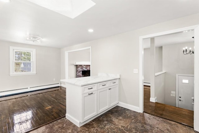 765 S Mammoth Rd, Manchester, NH 03109 - kitchen with a peninsula, white cabinetry, baseboards, a baseboard heating unit, and light stone counters