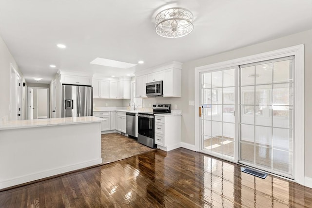765 S Mammoth Rd, Manchester, NH 03109 - kitchen with white cabinets, dark wood finished floors, baseboards, light countertops, and appliances with stainless steel finishes